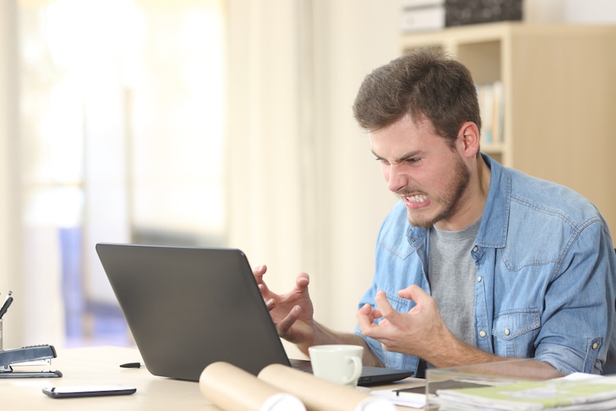 An angry man gesturing at his laptop